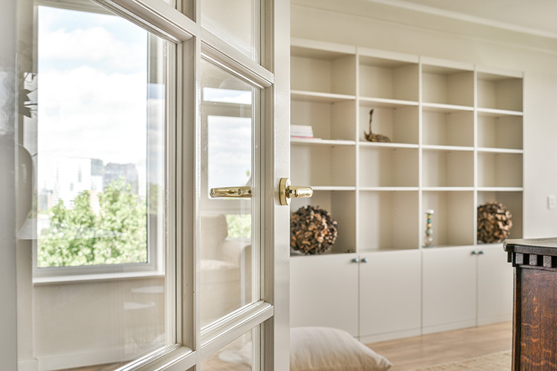 Built-in white bookshelves beside a window