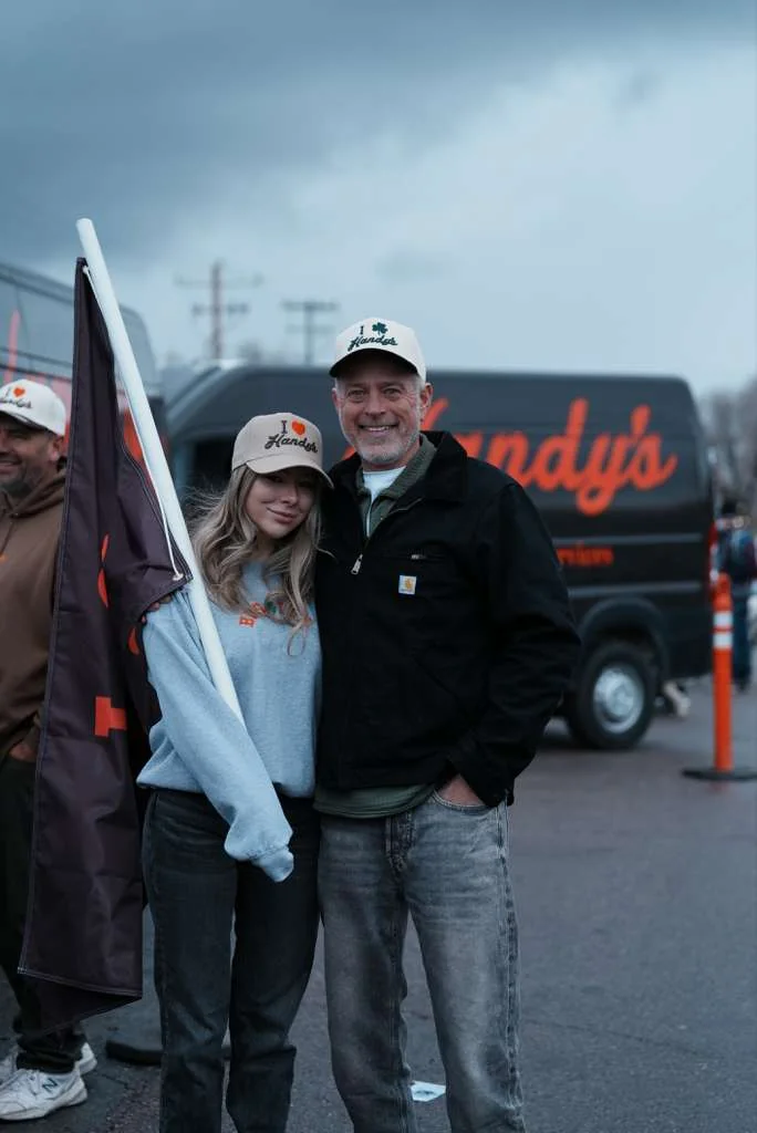 Two Handy's team members at a parade with the Handy's flag