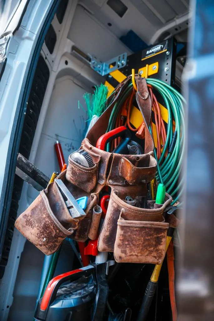 Leather tool belts hanging inside a Handy's van